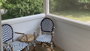 A room with a large window, wicker ceiling fan, and two chairs with patterned cushions. - Newly Renovated Quonnie Beach House -  QEBA Beach Pass & Pond Access (Charlestown)