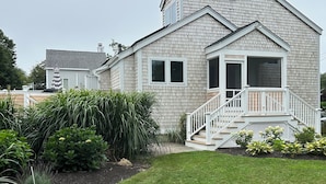 A two-story house with a covered porch and a small staircase leading to the entrance. - Newly Renovated Quonnie Beach House -  QEBA Beach Pass & Pond Access (Charlestown)