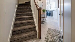 A staircase with carpeted steps leading to a landing with a wooden handrail.