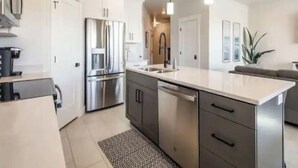A modern kitchen with stainless steel appliances, a central island, and pendant lighting.
