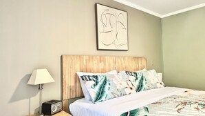 A bedroom with a wooden headboard, a bed with a floral bedspread, a bedside lamp, and a radio. - Old Town "Gem", Near Historic Downtown Saint Augustine (St. Augustine)