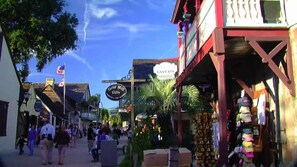 Une rue animée, bordée de boutiques, avec une enseigne indiquant « Grist Mill Gifts ».