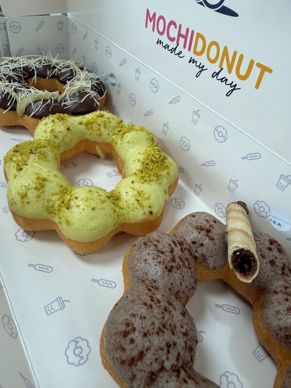 A box of assorted donuts with various toppings and designs.