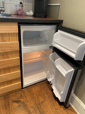 Un petit réfrigérateur doté de deux compartiments à portes, d’un plan de travail en bois et d’un évier de cuisine.