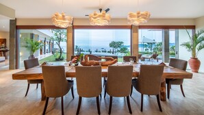 A dining area with a large wooden table, four chairs, and a view of the ocean. - Oceanview 4BR Villa,Infinity Pool in East Bali (Candidasa)