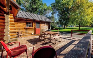 A log cabin with a wooden deck, picnic tables, and chairs. - Shell Town Cabin- Classis Log Cabin, Large Fireplace, Base of the Bighorns Location (Shell)