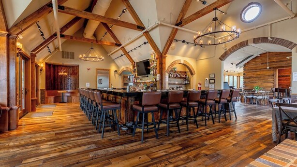 A spacious bar area with wooden flooring and a long counter, surrounded by multiple bar stools. - Great Shell Wyoming Escape- Large Family Retreat at the Base of the Bighorn Mountains (Shell)