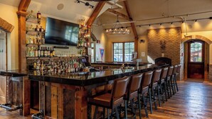 A bar area with a long counter, multiple stools, and a television mounted above the bar. - Great Shell Wyoming Escape- Large Family Retreat at the Base of the Bighorn Mountains (Shell)