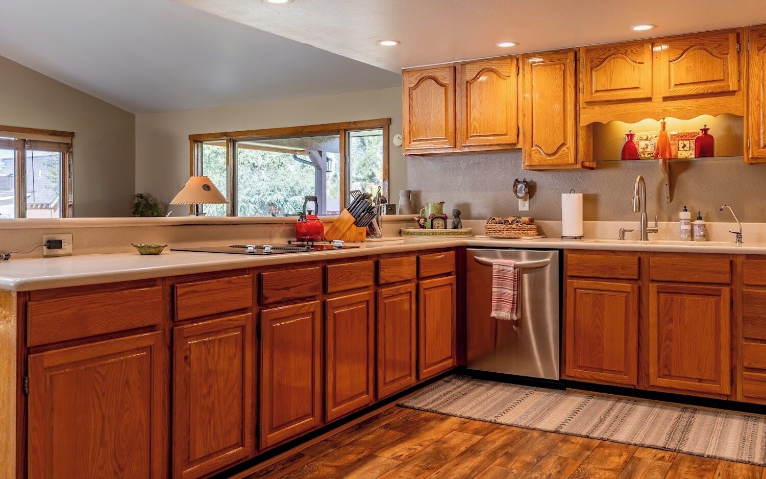 Una cocina moderna con armarios de madera, lavavajillas de acero inoxidable y un ventanal que proporciona luz natural.