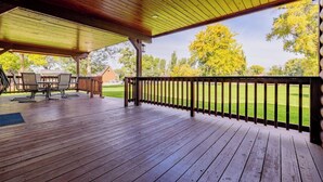 A wooden deck with a covered seating area, a barbecue grill, and a view of a grassy yard. - Great Shell Wyoming Escape- Large Family Retreat at the Base of the Bighorn Mountains (Shell)