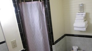A bathroom with a shower curtain, a toilet, and a towel rack with towels. - Royal Coach Motor Lodge (Hampton)