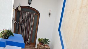 Un escalier orné de carreaux décoratifs, des plantes en pot et une porte agrémentée d’un rideau décoratif.