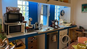 Une cuisine compacte équipée d’un four à micro-ondes, d’un grille-pain, d’une bouilloire et d’un lave-linge.