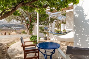 Eine Terrasse mit einer Hängematte, einem blauen Tisch und einem hölzernen Stuhl.