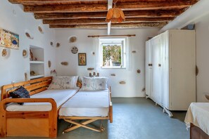 A room with a wooden bed, a white wardrobe, a window with a view, and a ceiling with exposed beams.