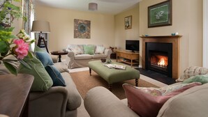 Una sala de estar acogedora con chimenea, un conjunto de sofás, una mesa de centro y un televisor.