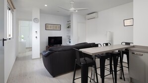 Ein modernes Wohnzimmer mit einer Couch, einem Esstisch und Barhocker.