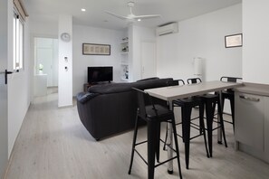 Un salon moderne avec un canapé, une table à manger et des tabourets de bar.