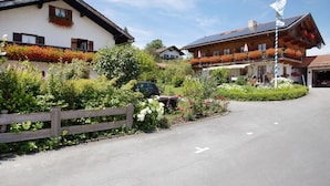 A rural village with traditional wooden houses, a paved road, and a flagpole. - Apartment 'Löwenzahn' with Mountain View, Terrace & Wi-Fi (Fischbachau)