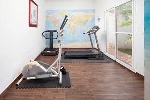 Une salle de sport équipée de matériel d’exercice, avec une carte du monde accrochée au mur et une grande fenêtre.