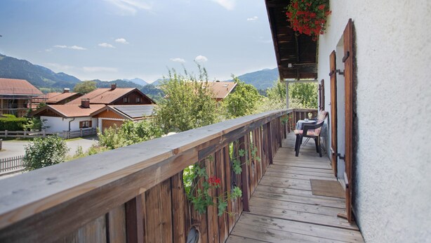 Un balcone in legno con vista su case e montagne.