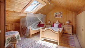 Una camera da letto con soffitto spiovente, un letto a baldacchino, comodini e un piccolo tavolo con tovaglia.