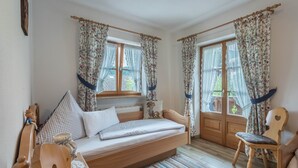 Een gezellige kamer met een houten bed, een stoel en een raam met gordijnen.