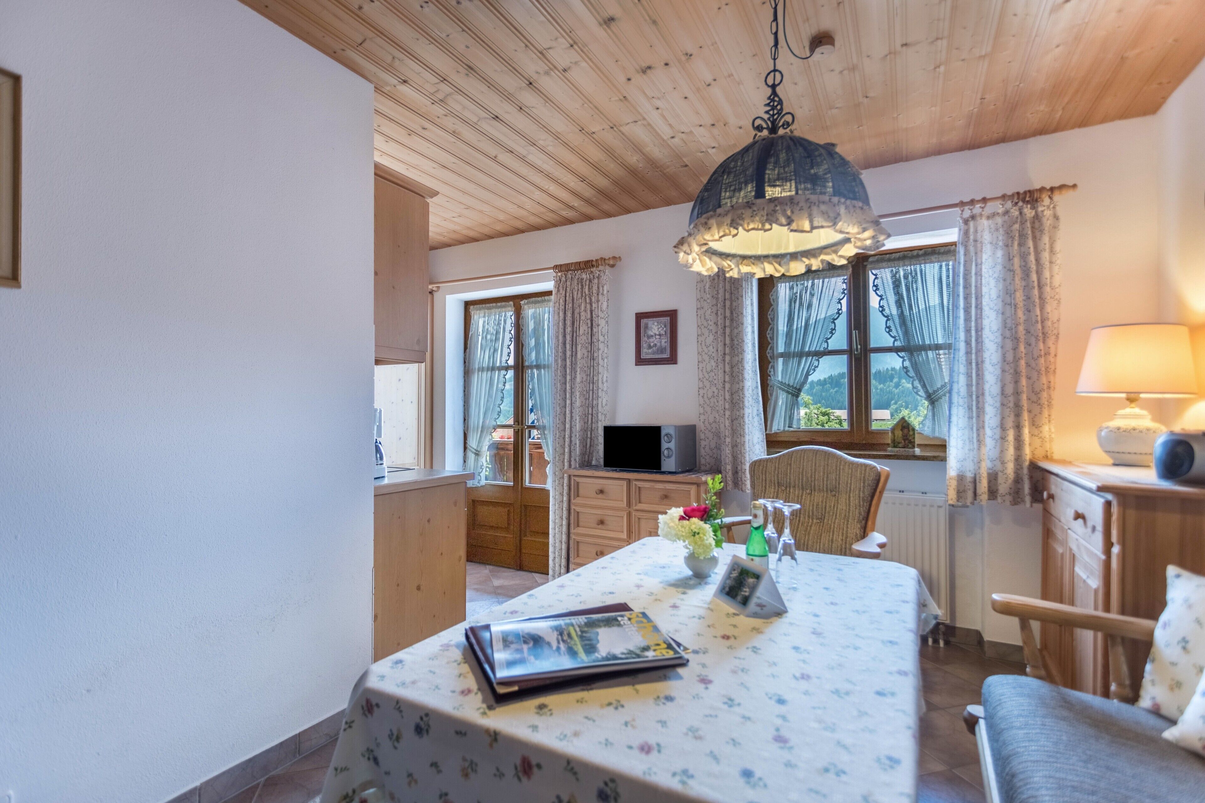 Una habitación acogedora con techo de madera, una mesa de comedor con mantel floreado, un televisor y una lámpara.