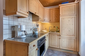 Une cuisine avec des meubles de rangement en bois, une cuisiniÚre, une machine à café et un évier.