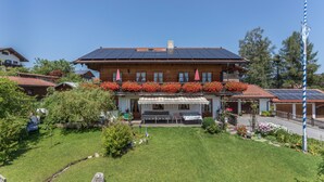 A large wooden house with a sloped roof, solar panels, and a well-maintained garden. - Apartment 'Enzian' with Mountain View, Balcony and Wi-Fi (Fischbachau)
