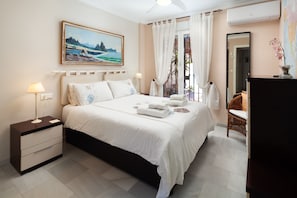 Quarto com cama, mesa de cabeceira, abajur e um quadro na parede.