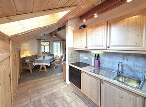 A wooden interior with a dining area, kitchen, and a skylight.