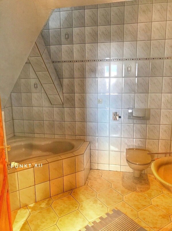 A bathroom with a bathtub, toilet, and a shower area.