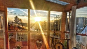 A room with large windows, a view of the sunset, and a wooden interior.