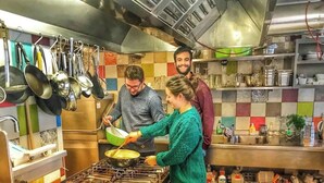 Una cocina con electrodomésticos de acero inoxidable, utensilios colgantes y un salpicadero de azulejos.