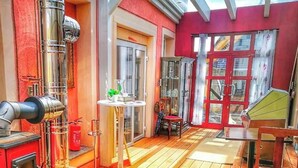 A room with a red wall, a glass door, a small table with a plant, and a wooden chair.