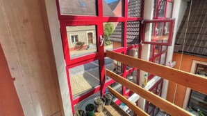 Ein mehrstöckiges Gebäude mit roten Fensterrahmen und einem Balkongeländer aus Holz.