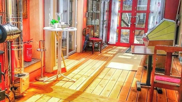 Ein Zimmer mit roter Wand, Glastür, kleinem Tisch mit Pflanze und Holzstuhl.