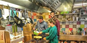 Une cuisine dotée d’appareils électroménagers en acier inoxydable, d’ustensiles suspendus et d’un dosseret carrelé.