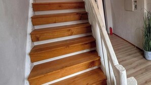 Eine Holztreppe mit weißen Geländern, die zu einem Raum mit weißer Wand und einer Topfpflanze führt.