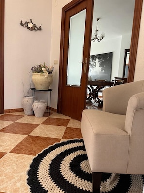 A living room with a beige sofa, a checkered floor, a black and white rug, and a large mirror on the wall.