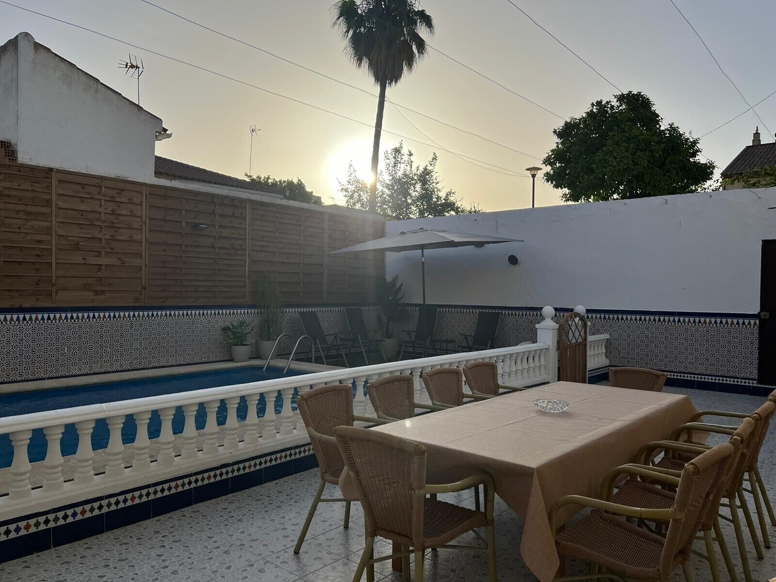 A patio with a pool, outdoor seating, and a decorative wall.