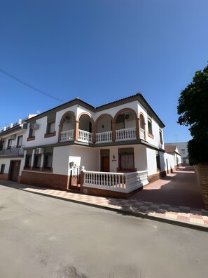 A two-story building with a balcony, a gated entrance, and a clear sky.