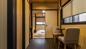 Un corridoio stretto con pavimento in legno che conduce a una stanza con un letto e una sedia.