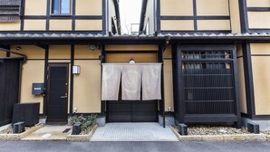 Un edificio tradizionale giapponese con facciata nera e gialla, una porta scorrevole e un piccolo giardino con rocce e piante.