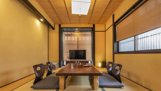 Una sala conferenze con tavolo in legno, tatami e schermo televisivo.
