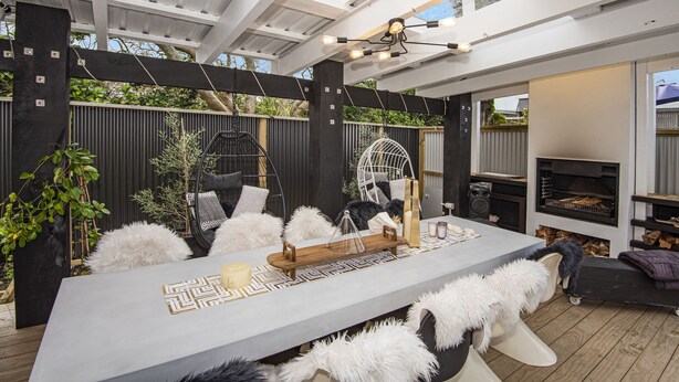 An outdoor patio with a central table, seating, a hanging chair, and a built-in grill. - Stylish Waterfront Studio Sanctuary! (Ngunguru)