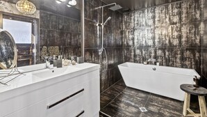 A modern bathroom with a large mirror, two sinks, a bathtub, and a shower. - Stylish Waterfront Studio Sanctuary! (Ngunguru)