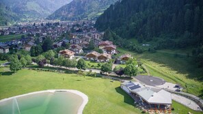 An aerial view of a residential area with houses, a swimming pool, and a building with solar panels. - Bucaneve - Lake View Apartment in Predazzo (Predazzo)