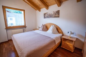 Une chambre à coucher avec un lit en bois, une fenêtre, un radiateur, une table de chevet et une lampe fixée au mur.